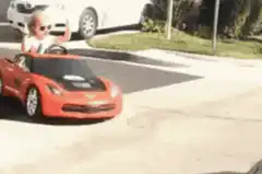 Toddler in toy car giving the finger