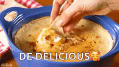 Hand dipping chip into cheesy dip