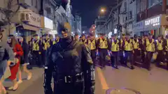 Batman walking down street with police