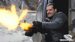 Man firing a large gun from a vehicle