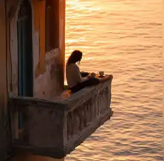 woman sitting on balcony at sunset