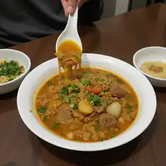 Lifting cheesy meatball soup with spoon