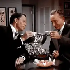 Two men drink from a large silver bowl