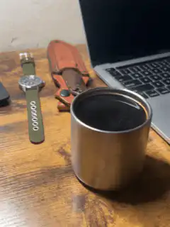 watch and knife next to coffee cup