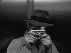 Man in fedora taking photo with flash