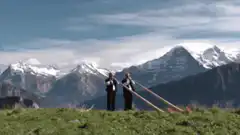 Two men playing alphorns in the mountains