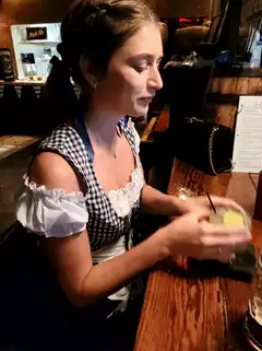 woman in dirndl drinks cocktail at bar