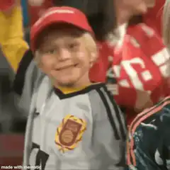 Young boy in red cap smiling and raising arm