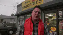 Man in red vest points down