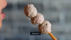 person eating fish balls on a stick