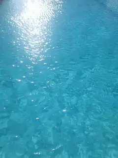 sunlight sparkling on blue pool water