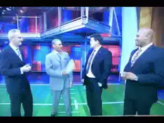 Man in grey suit hits another man with a paper