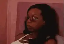 Woman in glasses looking shocked on bed