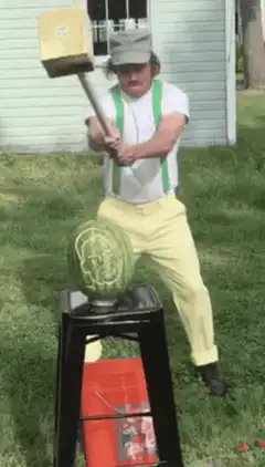 Man swings hammer at watermelon