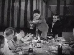 Man stands on table toasting with a trophy