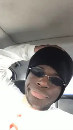 Man in beanie and sunglasses smirking