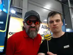 Two men posing with a bee prop