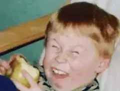 Boy laughing while eating an apple