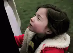 Girl in red coat looks up and smiles