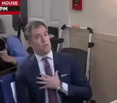 Man in suit touches chest and looks exasperated