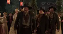 Three cowboys walk forward at night