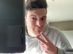 man making peace sign next to computer