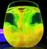 Green and yellow liquid swirling in a glass