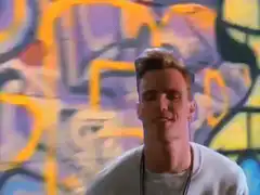 Man nodding and smiling in front of graffiti