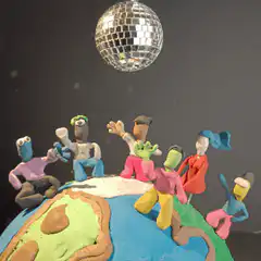 Claymation figures dancing on globe under disco ball