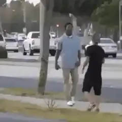 Man in bodysuit chases another man on sidewalk