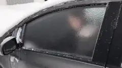 Hand reaches through frozen car window