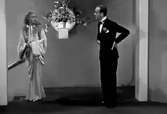 Man in tuxedo walks past woman in robe