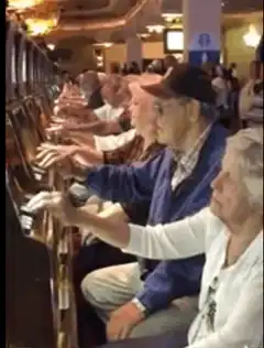 Elderly people playing slot machines in a row