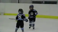 Two young kids playing ice hockey