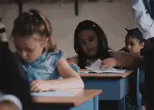 Girl in classroom looks back at classmate