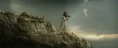 Woman playing violin on cliff during storm