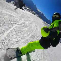 Snowboarder in neon green filming descent