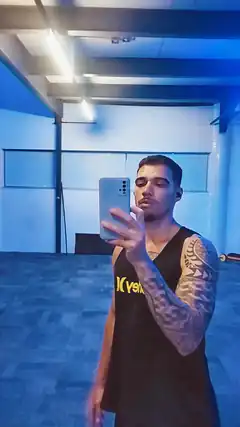Tattooed man taking mirror selfie in blue room