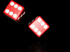 Two red dice rolling on black surface