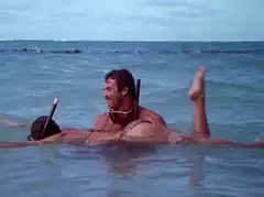 man reading book while floating on woman in ocean