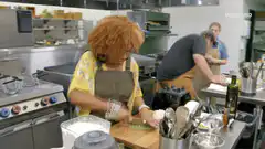 Woman chopping green herbs in kitchen