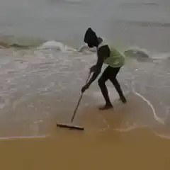 person sweeping sand on beach