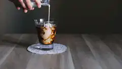 pouring milk into iced coffee