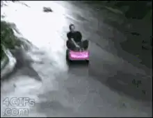 Man driving pink toy car down hill