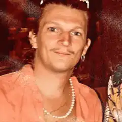 Man in orange shirt with pearl necklace