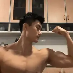 Shirtless man flexing bicep in kitchen