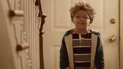 Boy raises hand in hallway