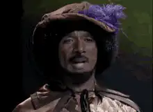 Sly Stone wearing a hat with purple feathers