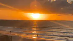 sunset over ocean with people on beach