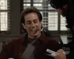 Jerry Seinfeld laughing with a pen in his mouth